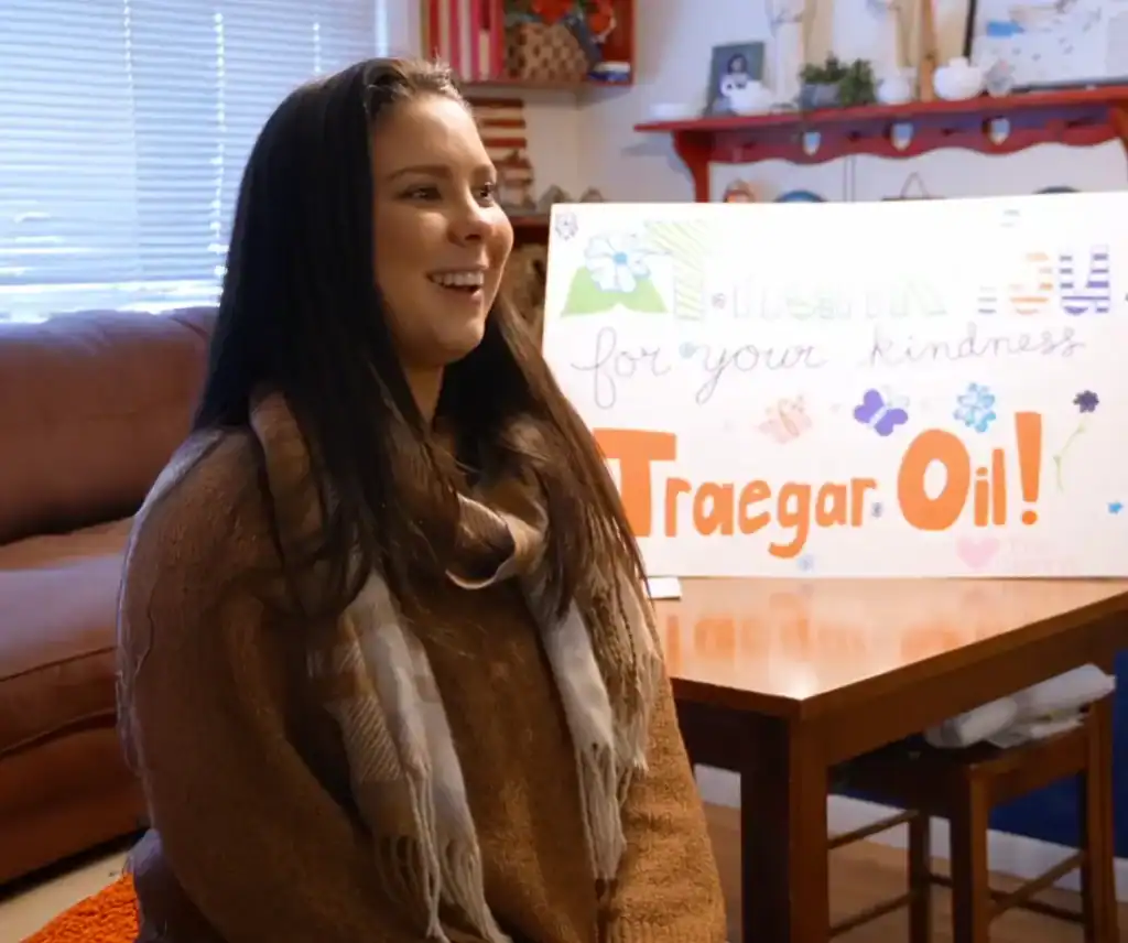Happy woman with kindness sign supporting Teegar Oil donation event.